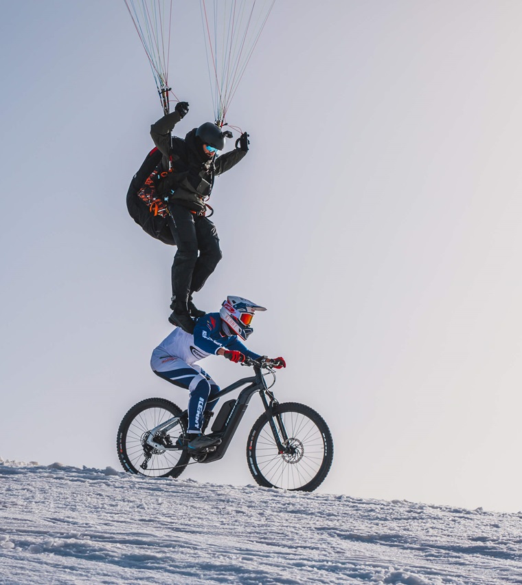 Tim Alongi et son parachute glissent au-dessus de Xavier Marovelli sur son vélo