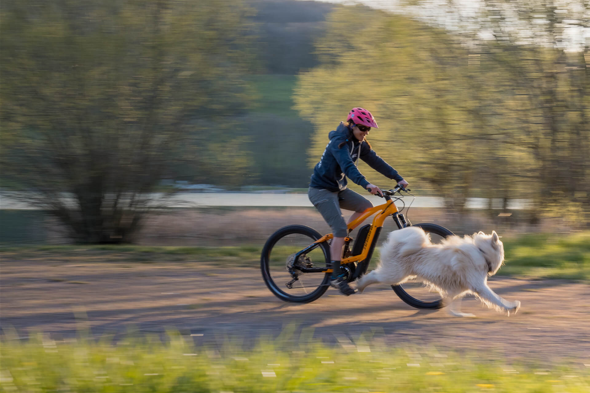 Caroline Delattre riding her Haibike AllMtn 4 eMTB with her dog running next to her
